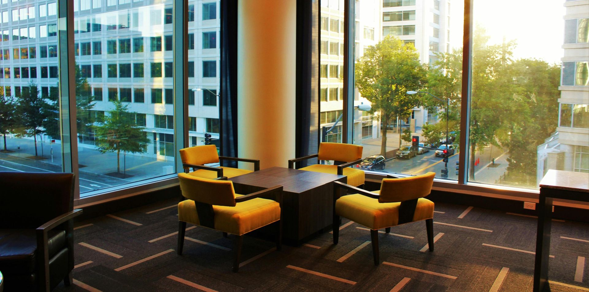 Contemporary hotel lounge featuring yellow chairs and cityscape view through large windows.